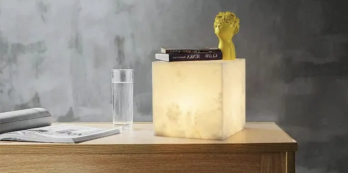 Cube-shaped alabaster table lamp on a wooden desk.